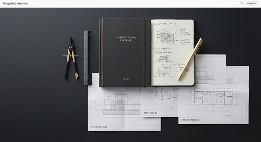A sleek, modern editorial flat lay on a matte black surface. It features a beautifully bound notebook, a minimalist gold pen, and several architectural blueprints slightly overlapping. The lighting is flat and even, characteristic of high-end product photography. The composition is highly geometric and structured, communicating precision, design thinking, and intellectual rigor.